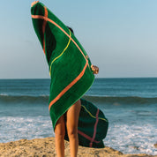 Person holding a green beach towel with yellow and cognac lines on a beach