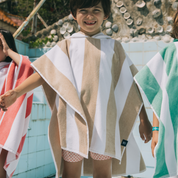 Child wearing a striped poncho with a pool in the background