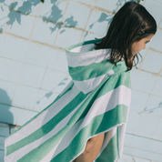 Kid wrapped in a green and white poncho by a pool.