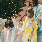 Children wrapped in colorful ponchos by a poolside