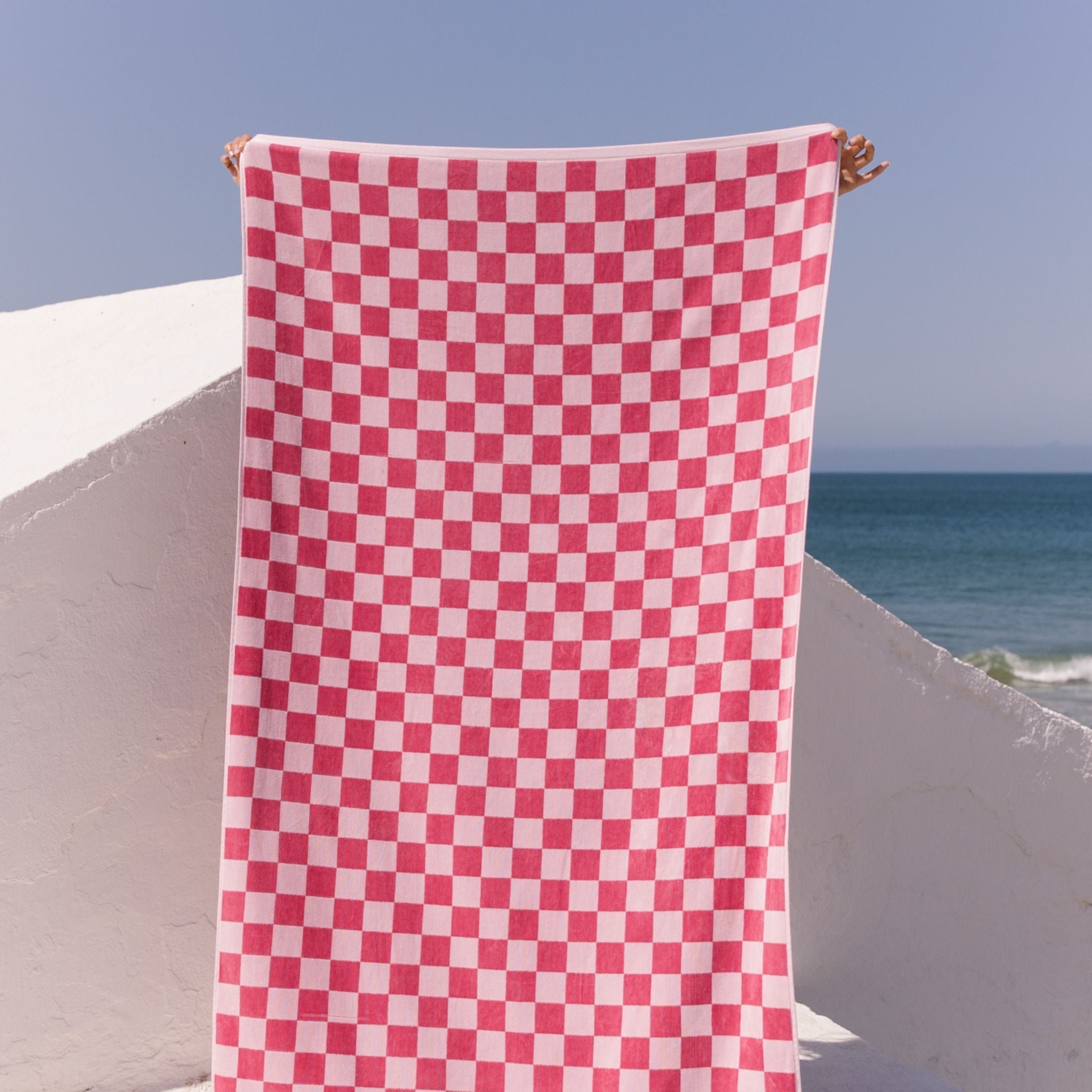 Pink checkered towel hanging by the ocean.