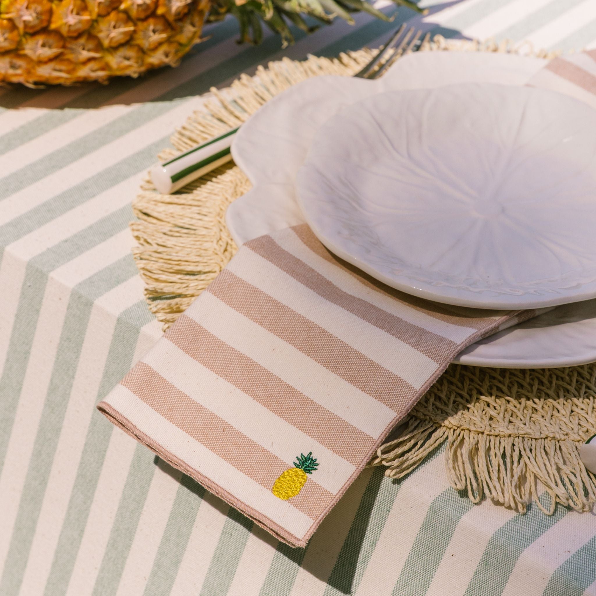 Striped napkin with pineapple design on a table setting with a plate.