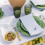 Table setting with green plates, white napkins, and a bowl of olives.