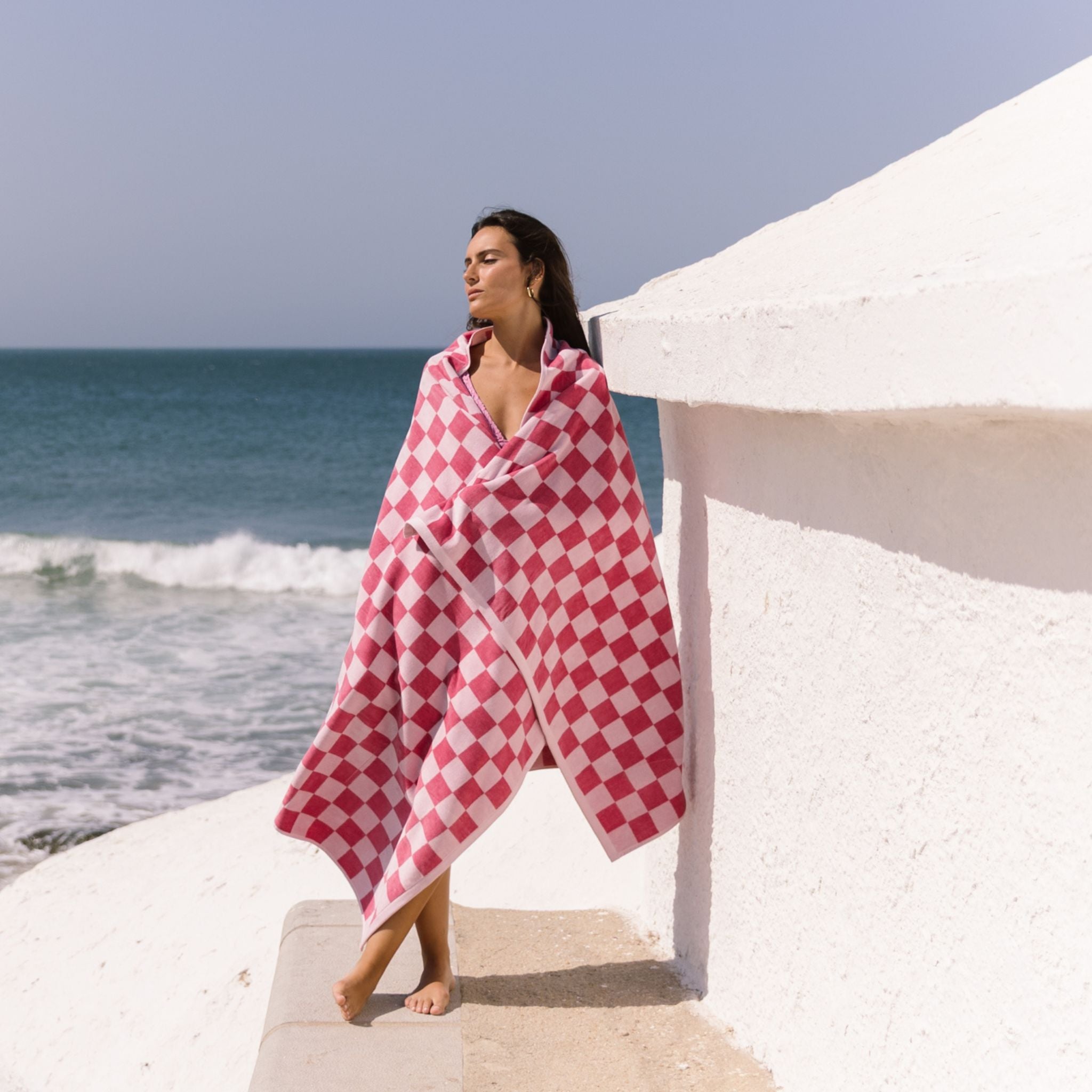 Woman wrapped in a pink checkered towel on a beach